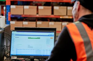 Whistl employee looking at computer screen showing a warehouse and order management system
