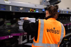 A female employee collects mail items from a mail sortation machine in Bedford, UK. 
