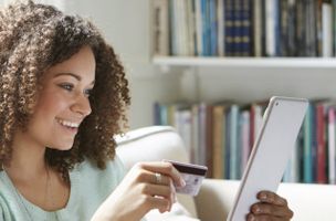 woman with curly brown hair buying goods online, holding a credit card