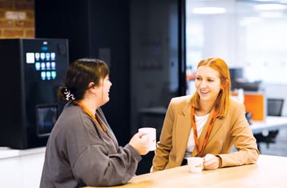 Smiling Whistl employees converse over a coffee