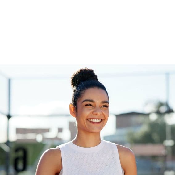 A lady smiling, wearing sports clothing, holding a bottle of water